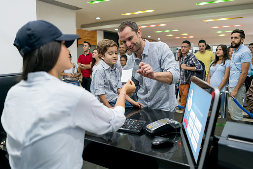 Portrait of a happy father and son buying movie tickets at the cinema - entertainment concepts. Image on screen was designed by us from scratch