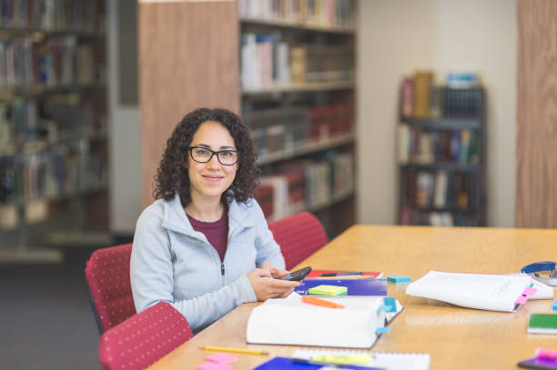 gli studenti universitari etnici aspettano che il suo gruppo di studio si mostri in biblioteca... - individual event women adult professional occupation foto e immagini stock