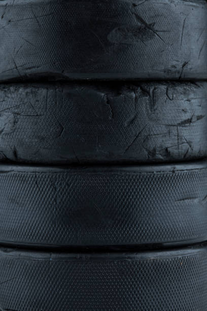 A close up detail shot of a stack of worn hockey pucks.