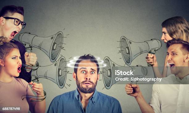 Group Of People Screaming In Megaphones At Scared Guy Stock Photo - Download Image Now