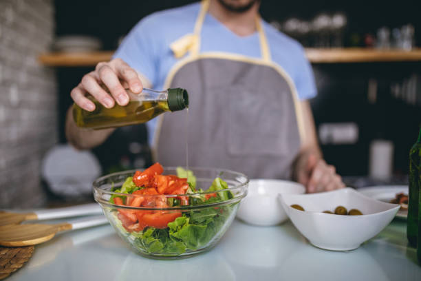 istock Man in apron preparing salad in kitchen 688790212