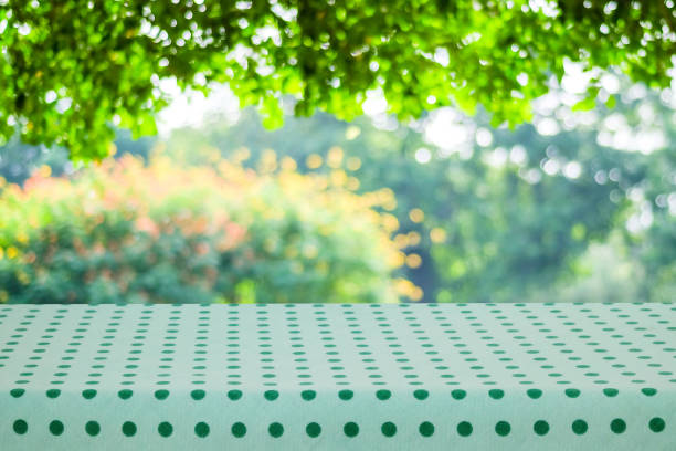Picnic checkered green folded towel cloth on wooden table empty space blurred natural background.