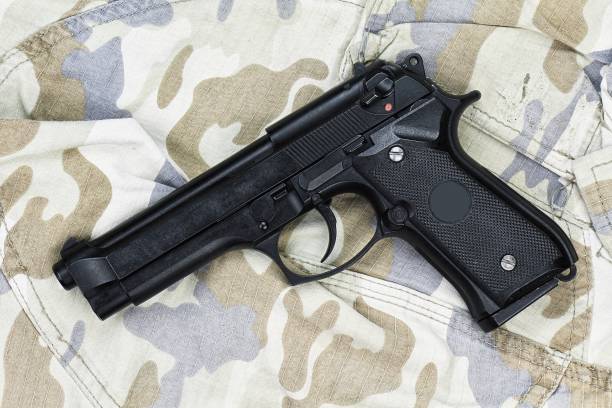 pistola semiautomatica su sfondo mimetico, pistola a trama militare, pistola da 9 mm, pistola moderna dell'esercito degli stati uniti m9 - handgun gun m9 9mm foto e immagini stock