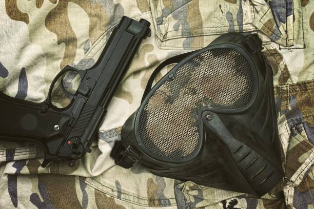 airsoft protection mask, terrorist mask and 9mm pistol (m9 handgun) on camouflage background. - m9 imagens e fotografias de stock