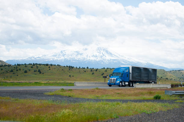 istock Semi trucks moving on turning wide highway with mountains background 688818926