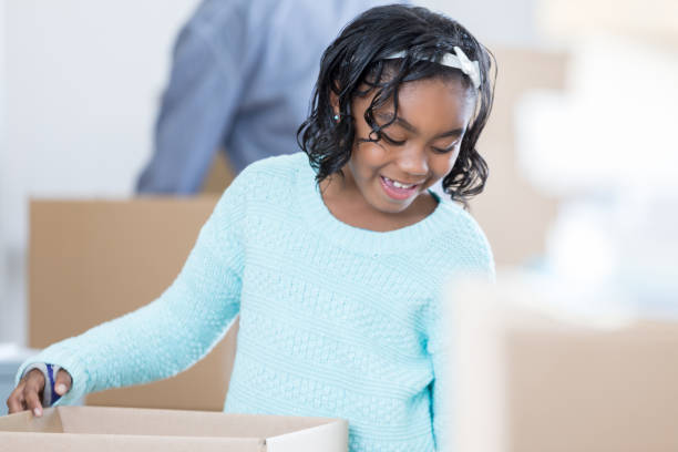 istock Happy elementary age girl unpacks boxes in new home 688821444