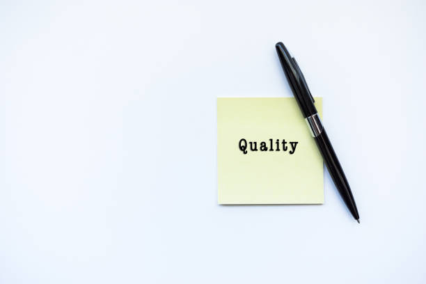 istock QUALITY word concept on sticky note and a pen over top view flat lay isolated on white background. 688831432