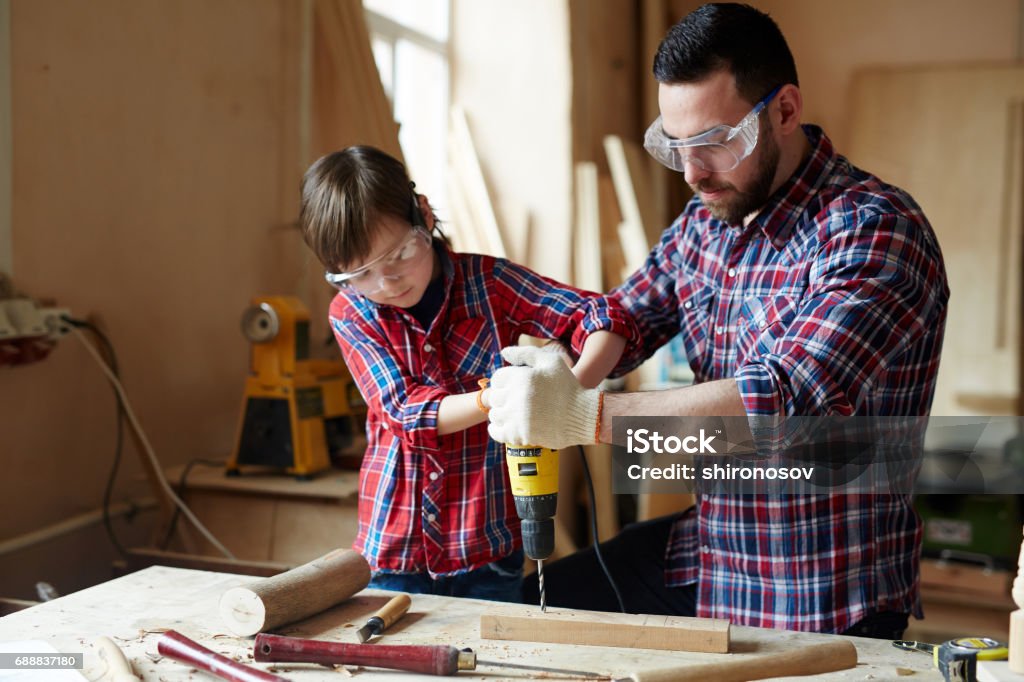 Drilling plank Little boy helping his father drill wooden plank together Work Tool Stock Photo