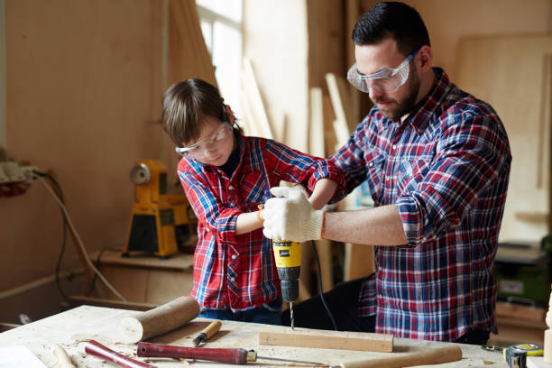 Drilling plank Little boy helping his father drill wooden plank together drill team stock pictures, royalty-free photos & images