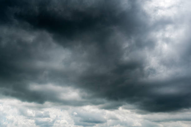 istock clouds with background,sunlight through very dark clouds background of dark storm clouds, black sky Background of dark clouds before a thunder. 688844028