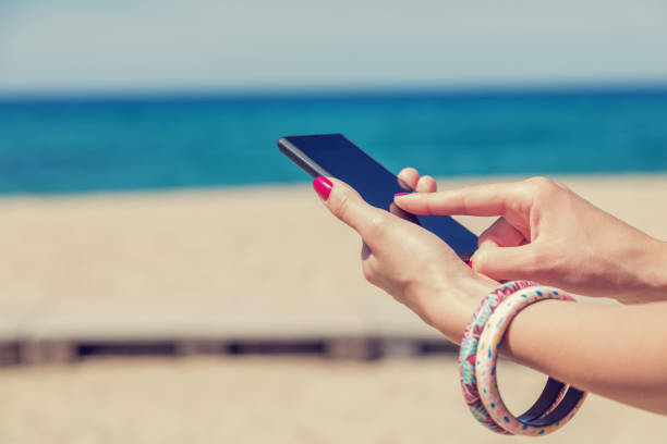 istock Girl holding a cellphone with sea/ocean background. 688844462