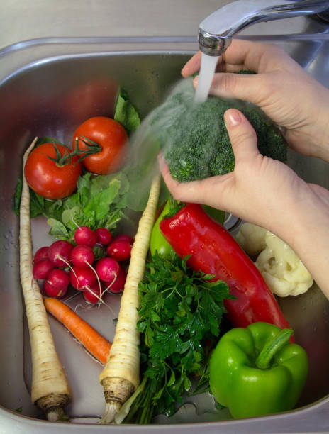 istock Female hands washing fresh vegetables in kitchen sink 688857366