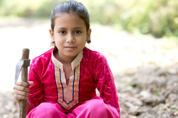Portrait of Indian girl holding garden hoe