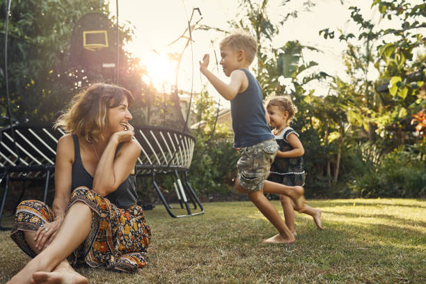 Letting them do their thing Shot of a young mother hanging outside with her son and daughter trampoline stock pictures, royalty-free photos & images