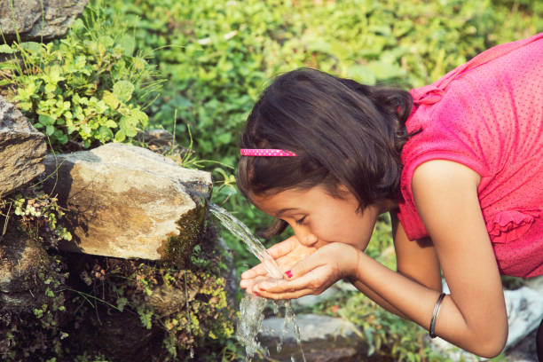 istock Girl drinking water from natural water source 688874346