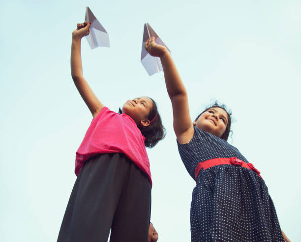 istock Girls throwing paper airplane 688874644