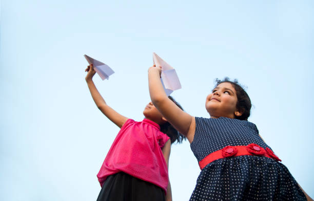 istock Girls throwing paper airplane 688874682