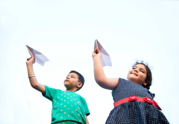 istock Girl and boy throwing paper airplane 688874830
