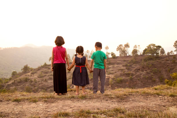 Rear view of Indian girls and boy holding hands on field