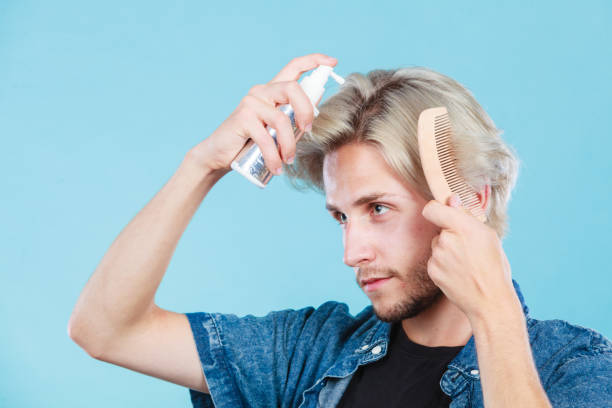 istock Man applying spray cosmetic to his hair 688877782