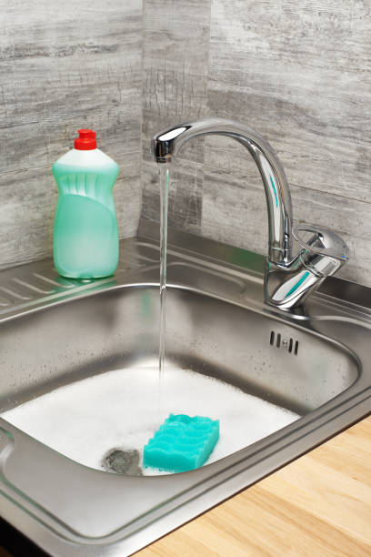 istock Kitchen sink with foam, tap, green sponge and detergent 688879222