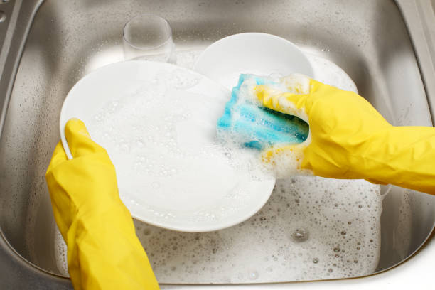mains dans la plaque de lavage jaune de gants contre l'évier de cuisine - protective glove washing up glove cleaning latex photos et images de collection