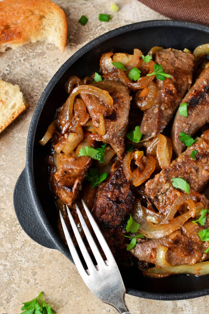 istock Fried liver with onions and apples on a concrete background 688886030