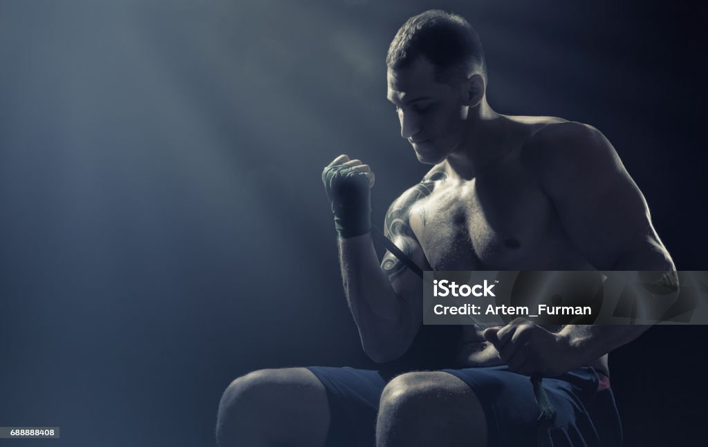 Fighting preparation Boxer putting on straps preparing for combat on a dark background Anaerobic Exercise Stock Photo