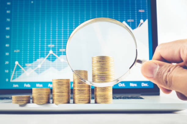 istock Male hand holding magnifying glass  with coin stacked 688889044