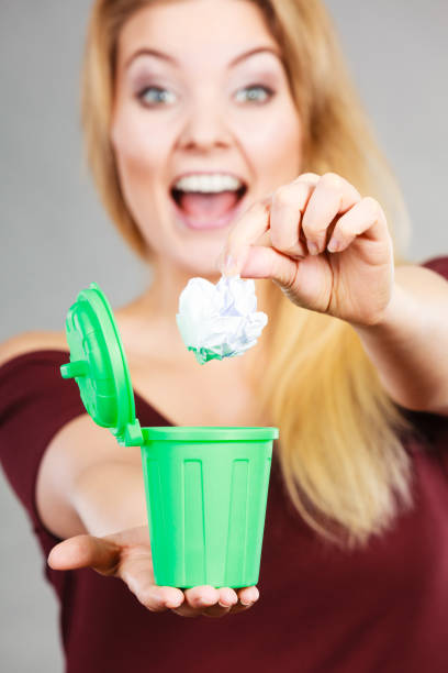istock Woman putting paper into small trash can 688897102