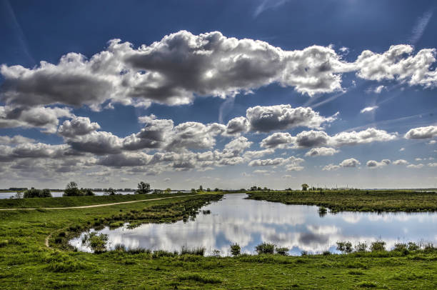 Clouds reflecting Wide open landscape on the island of Tiengemeten with clouds and blue sky relecting in a shallow lake tiengemeten stock pictures, royalty-free photos & images