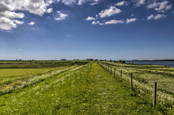 Dyke in Springtime Hiking trail on a dyke in springtime in an otherwise extremely flat landscape on the island of Tiengemeten, The Netherlands tiengemeten stock pictures, royalty-free photos & images