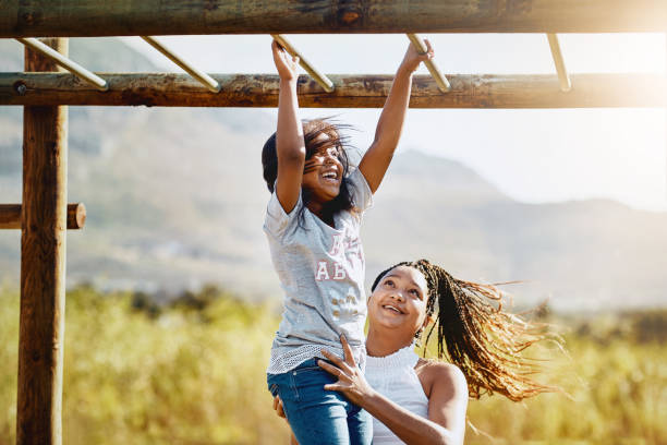 Mom will always be around to support her little monkey Cropped shot of a mother holding her daughter as she climbs a jungle gym at the park jungle gym stock pictures, royalty-free photos & images