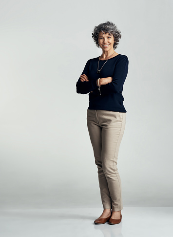 Studio portrait of a confident mature woman posing against a gray background