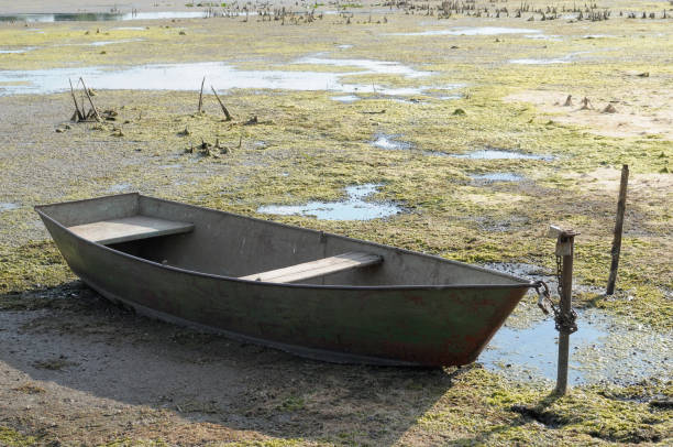 istock drought in the hot summer. Dried river without water and boat 688917648