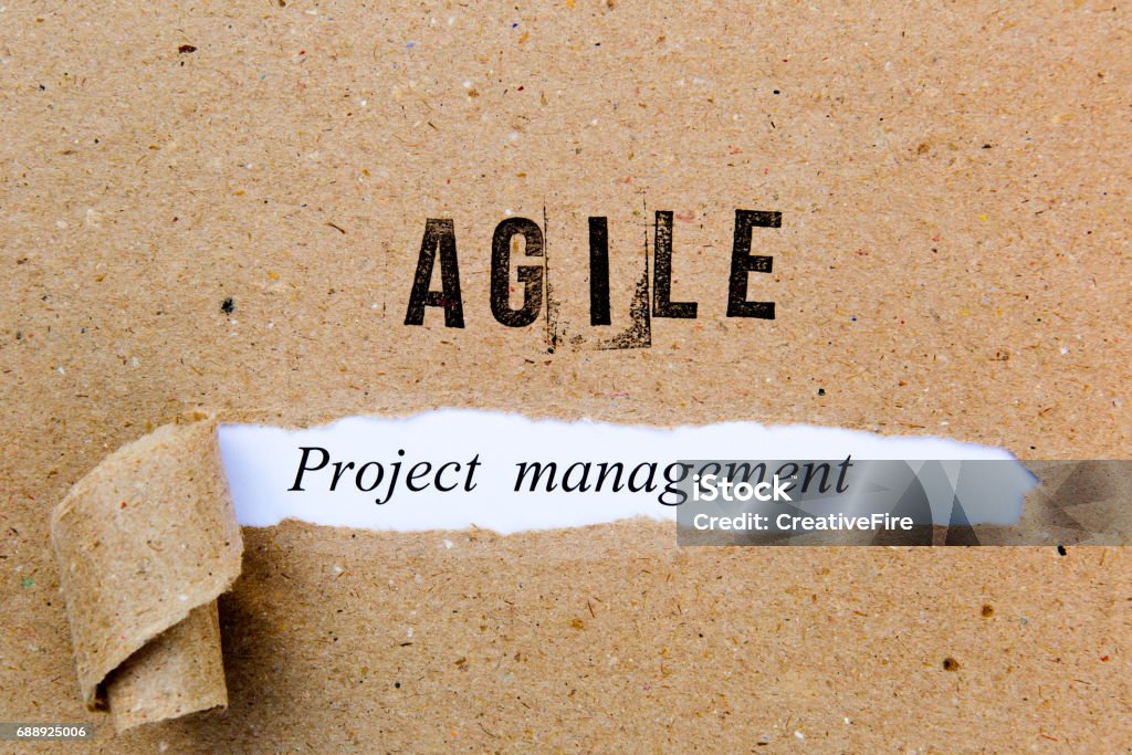 Agile Project Management - printed text underneath torn brown paper with Agile printed in ink Agile Methodology Stock Photo