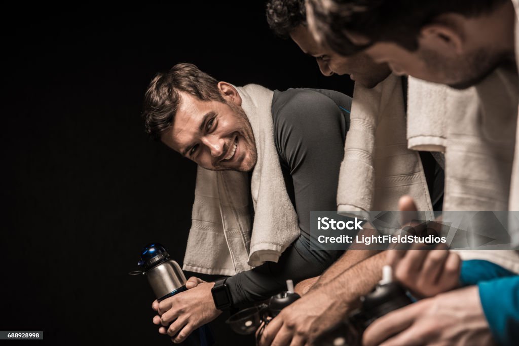 Handsome young athletes resting at gym locker room Male Friendship Stock Photo