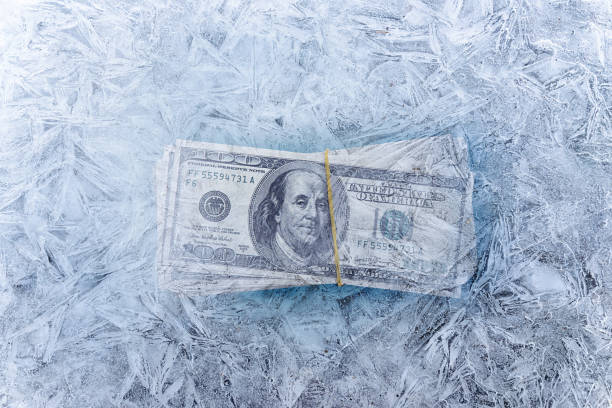 смешанное изображение замороженных долларов в кубике льда, глобальный экономический кризис и сокращения концепций - frozen currency finance ice стоковые фото и изображения