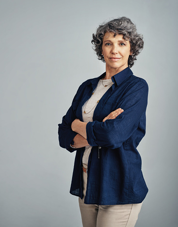 Studio portrait of a confident mature woman posing against a gray background