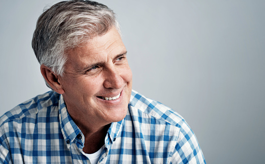 Studio shot of a happy mature man posing against a gray background