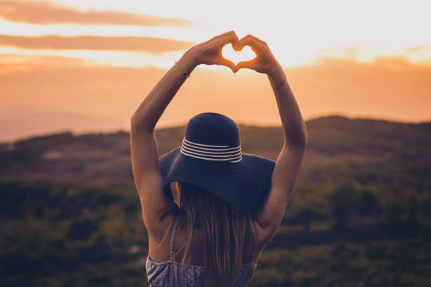 istock Woman with a hat making heart with her hands in the forest 688945410