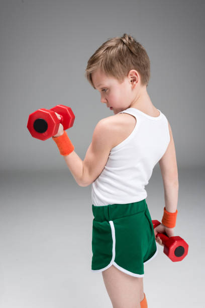 istock side view of active boy training with dumbbells isolated on grey 688948878