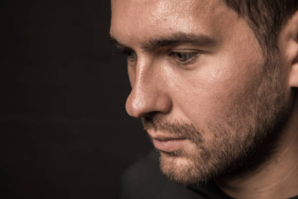 istock Thoughtful young man, close-up portrait on black 688952432