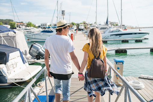 Young couple in love walking through the marina and enjoying the time together