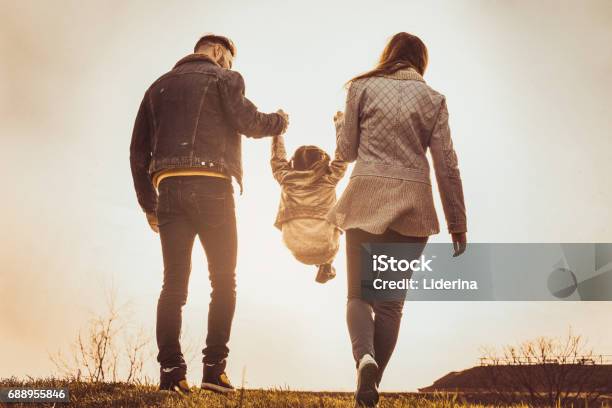 Padres Felizes Jugando Con Su Hija En El Parque Los Padres Elevar En El Aire Una Niña Foto de stock y más banco de imágenes de Vista posterior