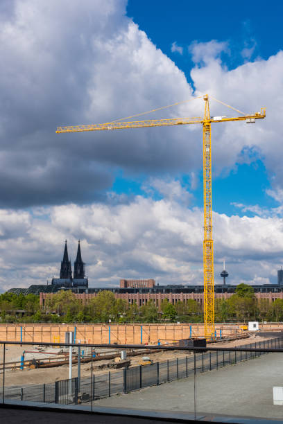 Skyline of Berlin with a construction site in the foreground. There are cranes rising high into the sky and the iconic TV tower in the background. Berlin is a vibrant city and is constantly growing with new buildings being built every day.