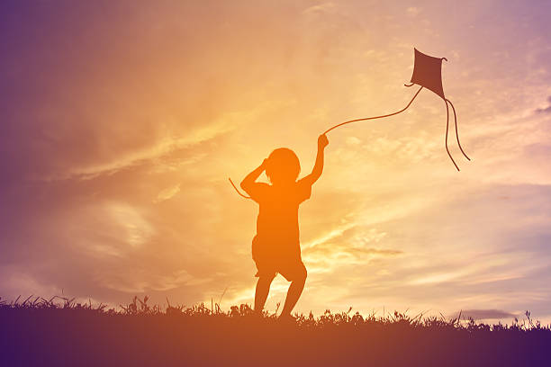 istock Silhouette Of Child Flying A Kite At Sunset 688966551