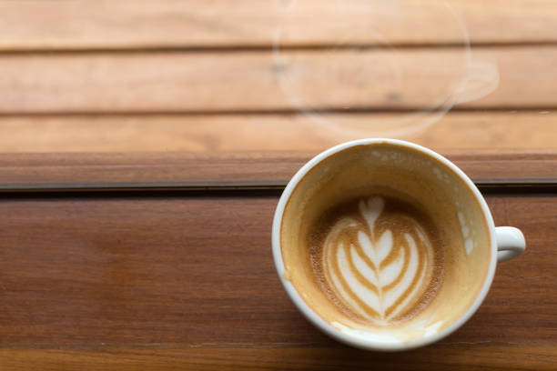 heart drawing latte art coffee cup on side of window.