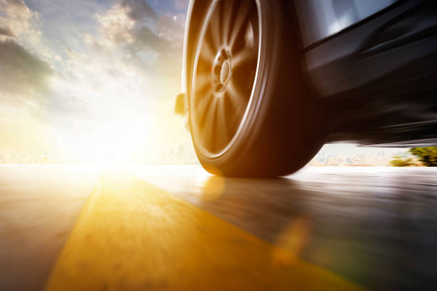 Low angle side view of car Low angle side view of car driving fast at sunset with motion speed effect . car wheel stock pictures, royalty-free photos & images