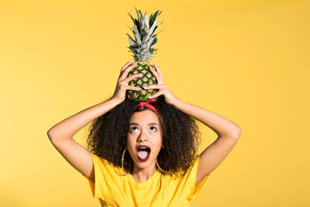 istock Surprised young afro woman holding pineapple on head 688996668